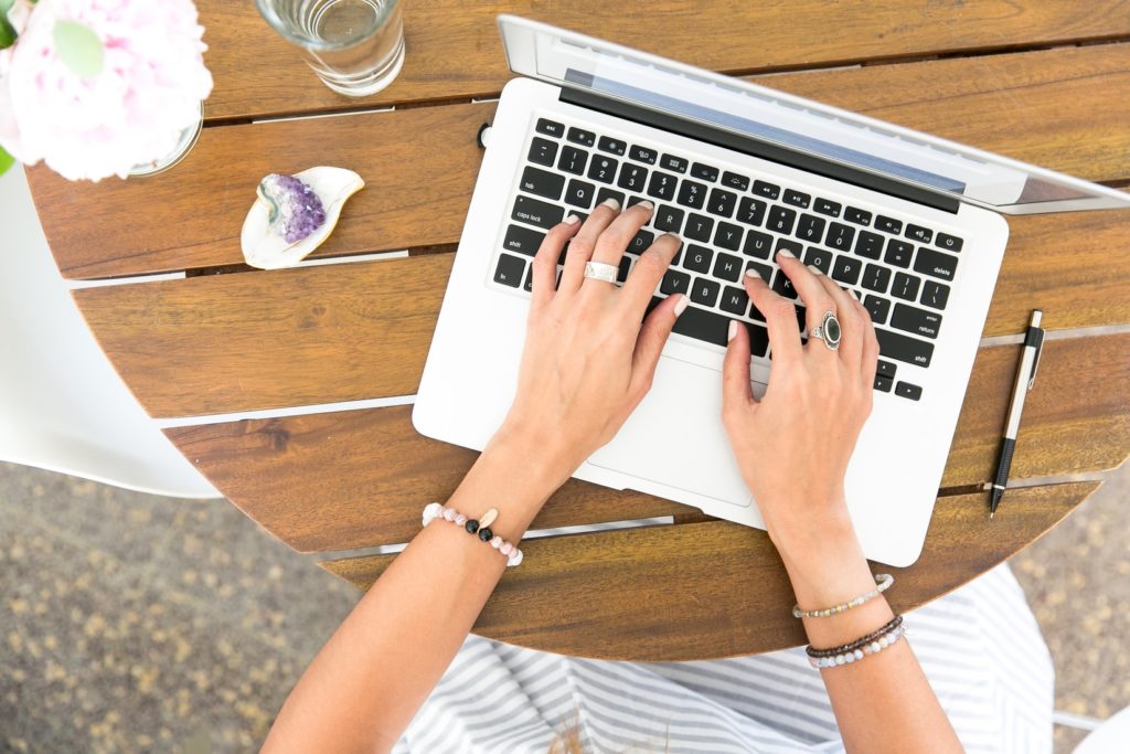 woman's hands typing on white macbook. searching for optimal keywords